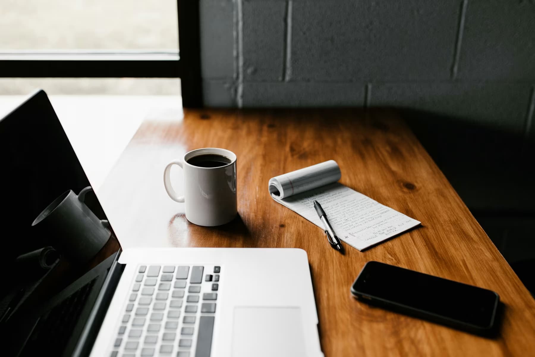 A laptop, notebook, and coffee on a founder’s desk